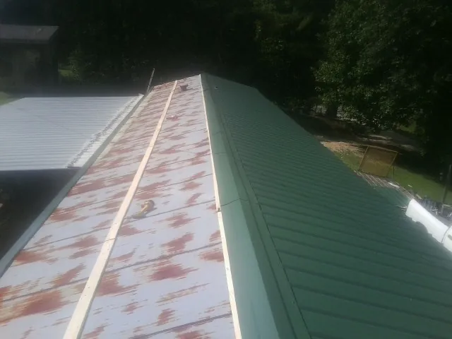Old rusted panels beside newly installed green metal roofing — Wind Damage Roof Repair by Roofing Brothers in Bartonsville