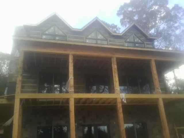 Dormers and porch framing on a large log home under construction — Roof Coating work by our crew in Bartonsville