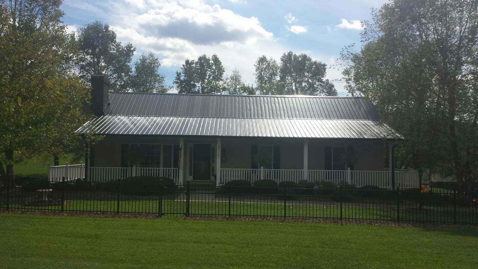 Gray metal roof on a brick ranch with a full width front porch — Gutter Guard Installation work by our crew in Bartonsville