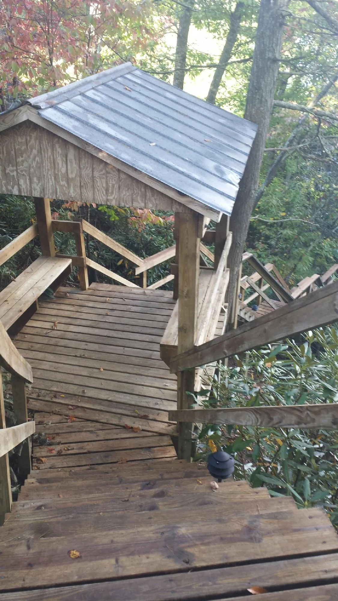 Metal roofed shelter over wooden steps on a wooded walkway — Skylight Repair & Installation work by our crew in Bartonsville