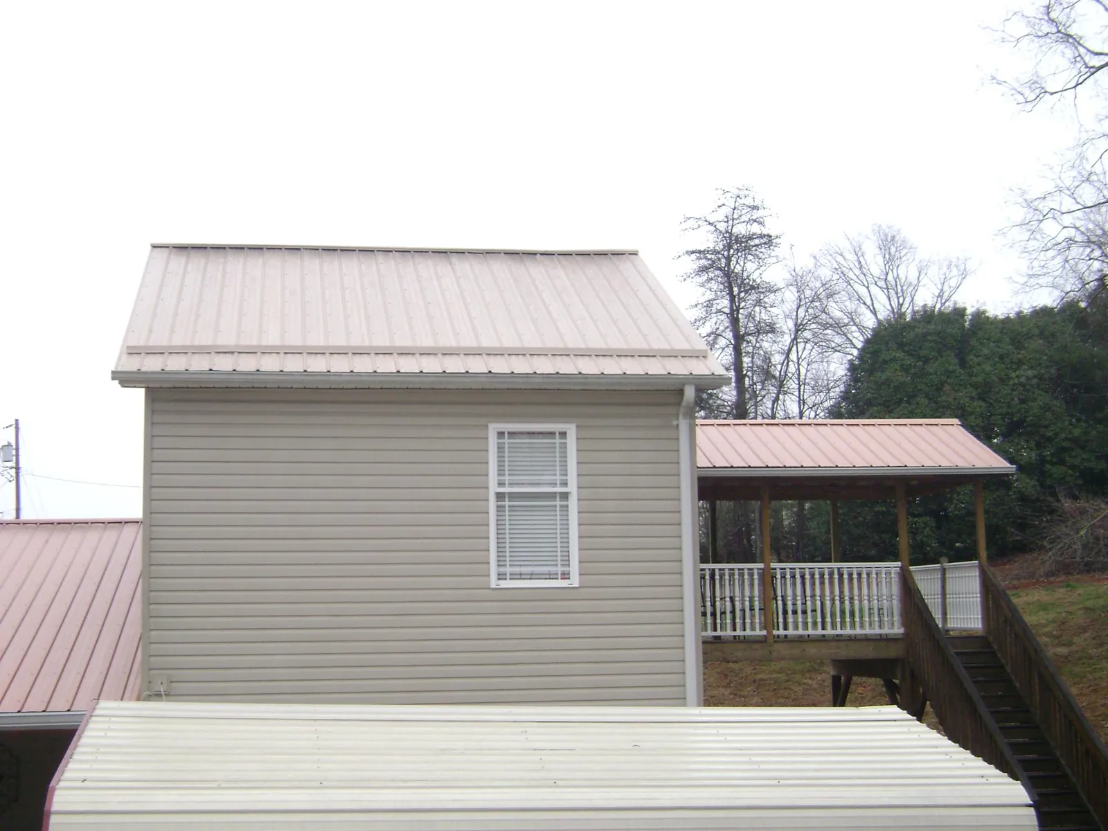 Tan metal roofs on a two story addition and attached porch, from a Roof Replacement job in Bartonsville