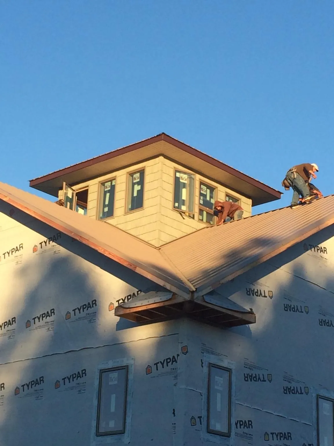 Roofers working around a rooftop cupola on a new metal roof at sunset — Roof Waterproofing in Bartonsville by Roofing Brothers